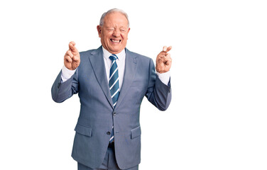 Senior handsome grey-haired man wearing elegant suit gesturing finger crossed smiling with hope and eyes closed. luck and superstitious concept.