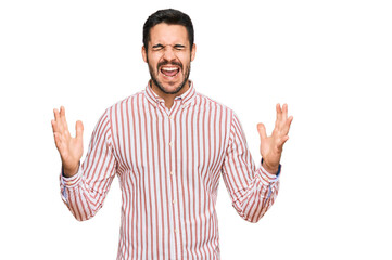 Fototapeta premium Young hispanic man wearing business shirt celebrating mad and crazy for success with arms raised and closed eyes screaming excited. winner concept