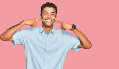 Young handsome african american man wearing casual clothes smiling cheerful showing and pointing with fingers teeth and mouth. dental health concept.