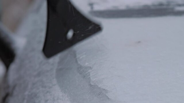 Person roof with black rubber ice scraper on cold winter day. Concept weather conditions