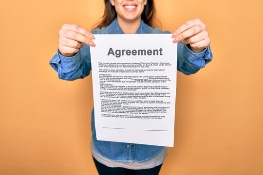 Woman holding agreement document paper standing over isolated yellow background