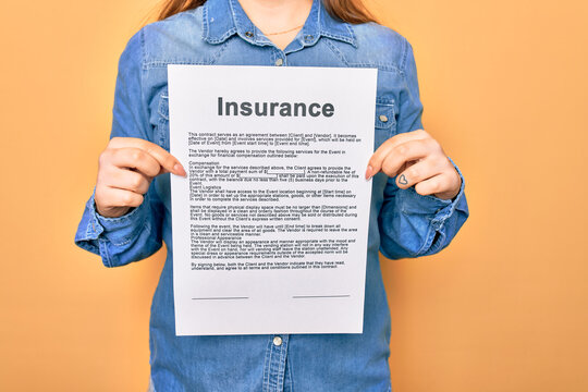 Woman holding insurance document paper standing over isolated yellow background
