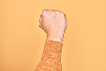 Hand of caucasian young man showing fingers over isolated yellow background doing protest and revolution gesture, fist expressing force and power