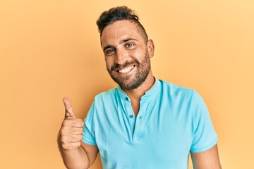 Handsome man with beard wearing casual clothes smiling happy and positive, thumb up doing excellent and approval sign