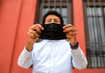 Naklejka premium Young latin man wearing a face mask for protective reasons during the covid 19 pandemic.