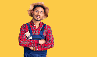 Handsome latin american young man weaing handyman uniform happy face smiling with crossed arms looking at the camera. positive person.