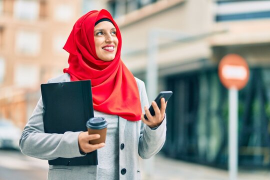 Young arab businesswoman using smartphone and drinking coffee at the city.