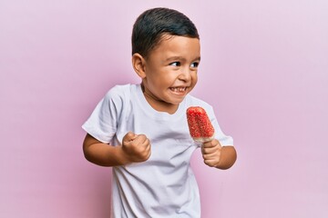 Adorable latin toddler holding ice cream screaming proud, celebrating victory and success very...