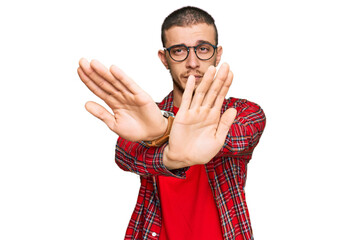 Hispanic young man wearing casual clothes rejection expression crossing arms and palms doing...