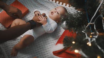 Baby first christmas. Daddy and newborn playing under decorated christmas tree. High quality photo