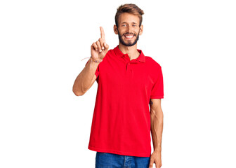 Handsome blond man with beard wearing casual clothes showing and pointing up with finger number one while smiling confident and happy.