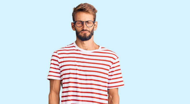 Handsome blond man with beard wearing casual clothes and glasses depressed and worry for distress, crying angry and afraid. sad expression.