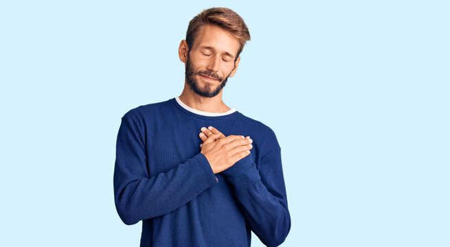 Handsome blond man with beard wearing casual sweater smiling with hands on chest with closed eyes and grateful gesture on face. health concept.