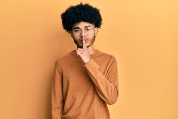 Fototapeta na wymiar Young african american man with afro hair wearing casual winter sweater asking to be quiet with finger on lips. silence and secret concept.