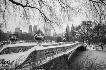 A Bow Bridge is covered in snow near the Lake