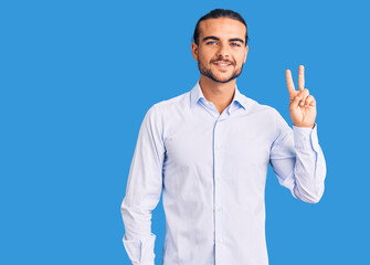 Young handsome man wearing business clothes smiling looking to the camera showing fingers doing victory sign. number two.