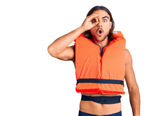 Fototapeta premium Young handsome man wearing nautical lifejacket doing ok gesture shocked with surprised face, eye looking through fingers. unbelieving expression.