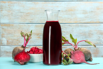 Fresh beet juice and raw vegetable on blue wooden table