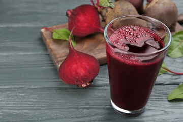 Fresh beet juice and raw vegetable on grey wooden table. Space for text