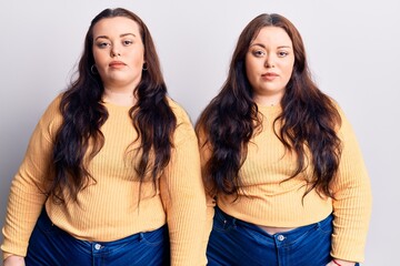 Young plus size twins wearing casual clothes looking sleepy and tired, exhausted for fatigue and hangover, lazy eyes in the morning.