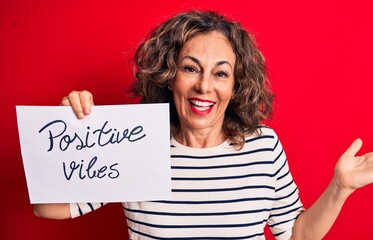 Middle age brunette woman asking for good attitude holding paper with positive vibes message...