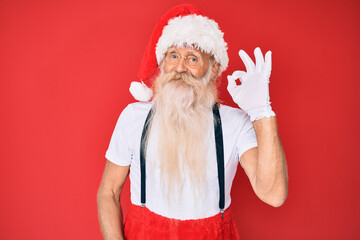 Fototapeta na wymiar Old senior man with grey hair and long beard wearing white t-shirt and santa claus costume smiling positive doing ok sign with hand and fingers. successful expression.