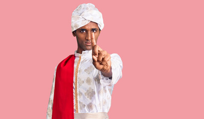 African handsome man wearing tradition sherwani saree clothes pointing with finger up and angry...