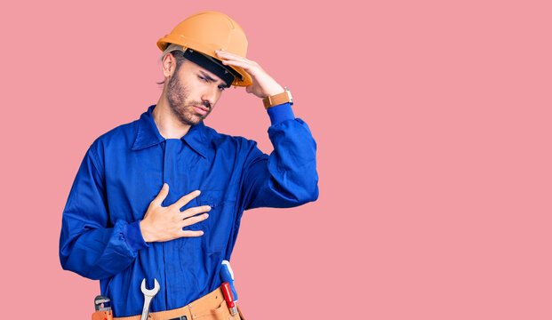 Young hispanic man wearing worker uniform touching forehead for illness and fever, flu and cold, virus sick