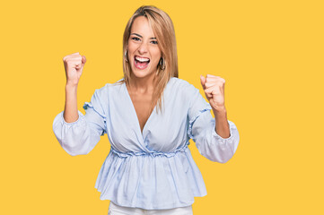 Obraz premium Beautiful blonde business woman wearing casual clothes screaming proud, celebrating victory and success very excited with raised arms