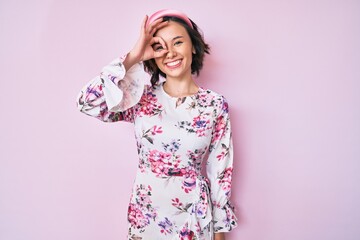 Young beautiful woman wearing casual clothes and diadem smiling happy doing ok sign with hand on eye looking through fingers