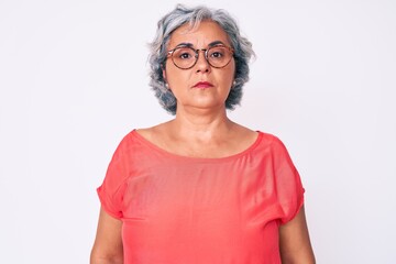 Senior hispanic grey- haired woman wearing casual clothes and glasses relaxed with serious...
