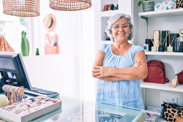 Middle age shop assistance woman working at the counter of retail shop smiling happy
