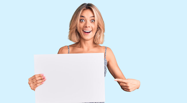 Beautiful caucasian woman holding blank empty banner smiling happy pointing with hand and finger
