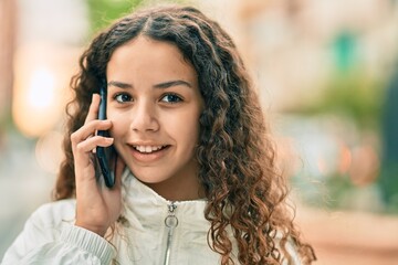 Beautiful hispanic girl smiling happy talking on the smartphone at the city.