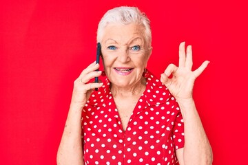 Senior beautiful woman with blue eyes and grey hair having conversation talking on the smartphone...