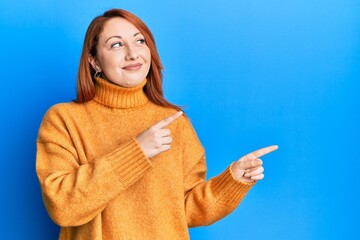 Beautiful redhead woman pointing fingers to the side smiling looking to the side and staring away...