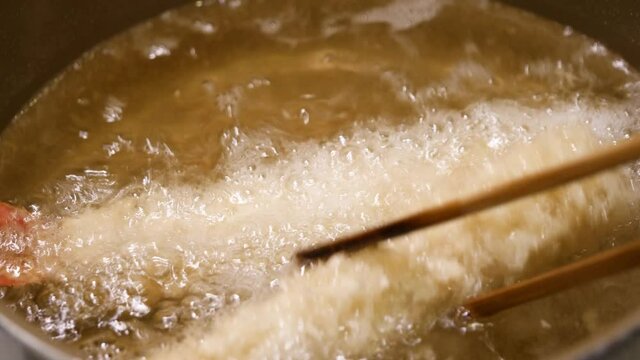 食用油で揚げてるエビフライを裏表返してる動画。
