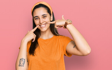 Young hispanic woman wearing casual clothes smiling cheerful showing and pointing with fingers teeth and mouth. dental health concept.