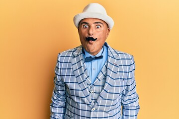 Mature middle east man with mustache wearing vintage and elegant fashion style making fish face with lips, crazy and comical gesture. funny expression.