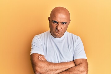 Mature middle east man wearing casual white tshirt skeptic and nervous, disapproving expression on face with crossed arms. negative person.