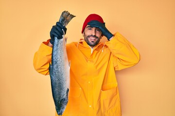 Handsome hispanic man with beard wearing fisherman equipment stressed and frustrated with hand on...