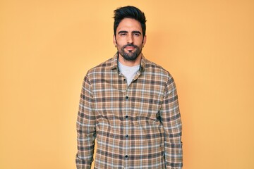 Obraz premium Handsome hispanic man with beard wearing casual clothes relaxed with serious expression on face. simple and natural looking at the camera.