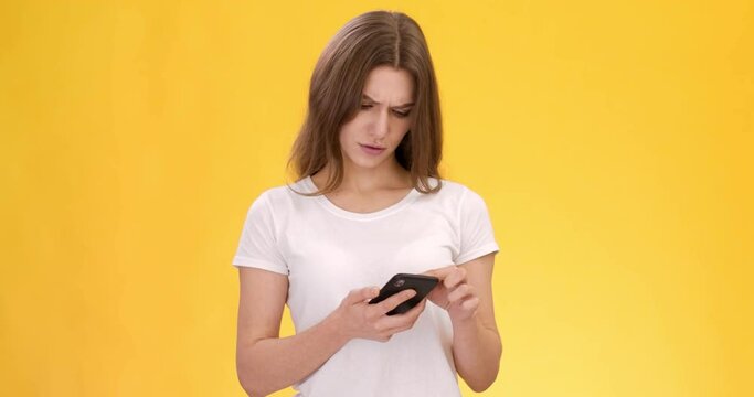 Young woman browsing social media, looking at awful news and shaking head in shock, orange studio background