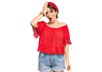 Young brunette woman with short hair wearing casual summer clothes and diadem surprised with hand...
