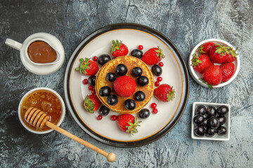 top view yummy pancakes with fresh fruits and honey on a light background fruit cake sweet