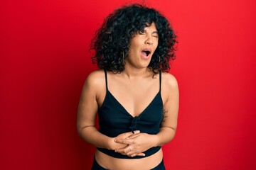Young hispanic woman wearing casual style with sleeveless shirt with hand on stomach because...