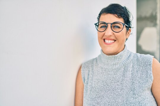 Young plus size woman smiling happy leaning on the wall at the city.