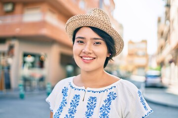 Young latin tourist girl on vacation smiling happy walking at the city.