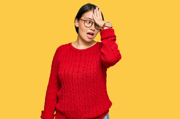 Young beautiful hispanic woman with short hair wearing casual sweater and glasses surprised with...