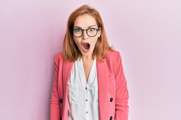 Young caucasian woman wearing business style and glasses afraid and shocked with surprise and amazed expression, fear and excited face.